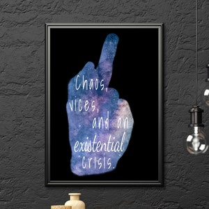 May include: A framed art print with the words "Chaos, vices, and an existential crisis" in white text. The image of a hand with the middle finger raised is filled with a galaxy design. The print is displayed on a black wall.