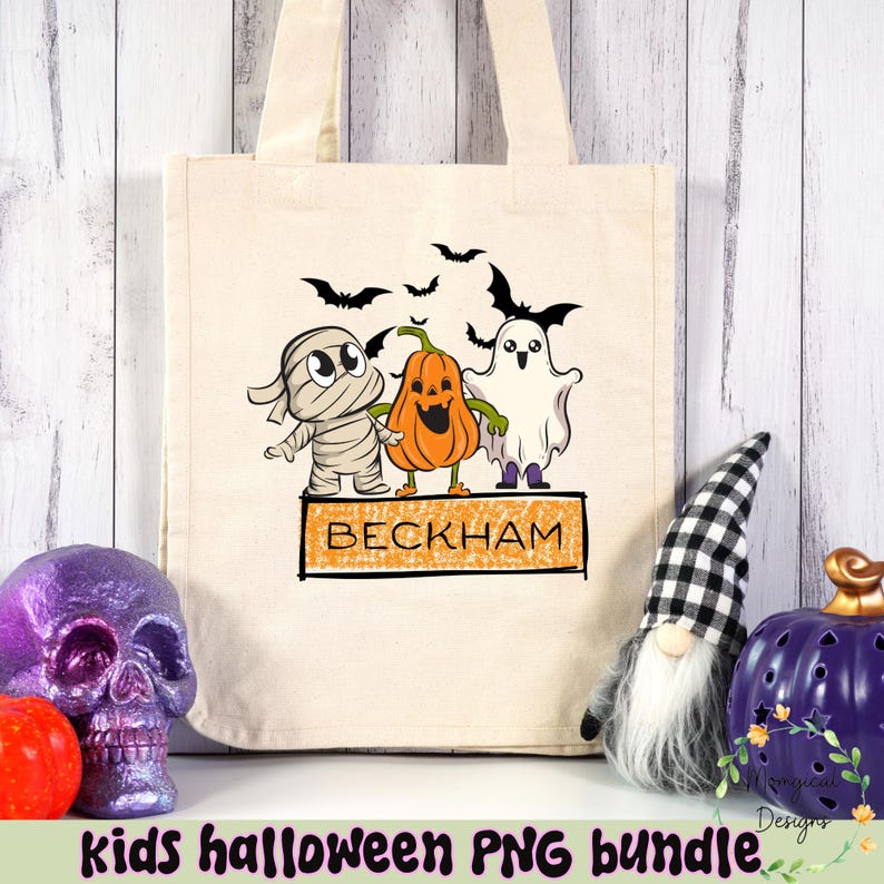 Puede incluir: Bolso tote de lona beige con un dise&ntilde;o de Halloween. Presenta una momia, una calabaza y un fantasma, con el nombre "BECKHAM" en un letrero. Murci&eacute;lagos negros vuelan por encima. Las palabras "kids halloween PNG bundle" est&aacute;n en la parte inferior.