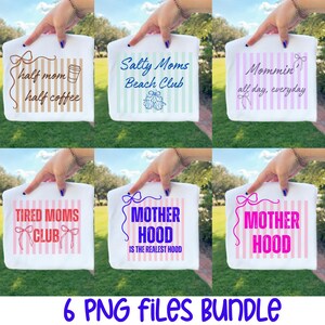 May include: A collection of six white t-shirts, each featuring a unique design and text. The shirts have various phrases like "Half Mom Half Coffee" and "Motherhood is the Realest Hood". The text is in different colors and fonts.