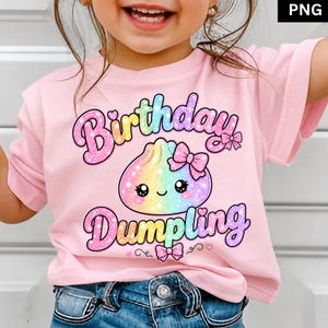 Peut inclure: Un t-shirt rose clair à manches courtes avec un motif de ravioli arc-en-ciel scintillant orné d'un nœud rose. Le texte "Birthday Dumpling" est imprimé dans une police multicolore et pailletée au-dessus et au-dessous du personnage.