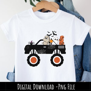 Op de afbeelding: Een wit T-shirt met een zwarte monstertruck die een mummie, een spook en drie pompoenen vervoert. De truck heeft spinnenwebben en een spin aan de zijkant. De tekst "DIGITAL DOWNLOAD - PNG FILE" staat onderaan de afbeelding.