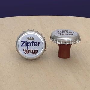 May include: Two silver bottle caps with a blue and white logo that says "Zipfer Urtyp" with a crown above the word "Zipfer".
