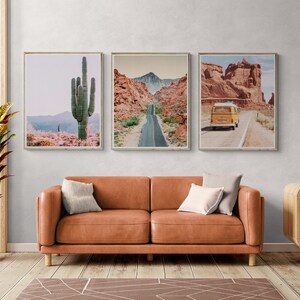 Puede incluir: Tres impresiones enmarcadas de paisajes des&eacute;rticos. Una muestra un gran cactus, otra una carretera a trav&eacute;s de un ca&ntilde;&oacute;n y la tercera una furgoneta amarilla en una carretera des&eacute;rtica. Las impresiones est&aacute;n sobre un sof&aacute; de cuero marr&oacute;n.