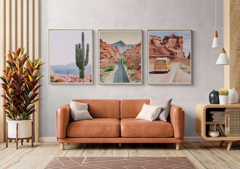Puede incluir: Tres impresiones enmarcadas de paisajes des&eacute;rticos. Una muestra un gran cactus, otra una carretera a trav&eacute;s de un ca&ntilde;&oacute;n y la tercera una furgoneta amarilla en una carretera des&eacute;rtica. Las impresiones est&aacute;n sobre un sof&aacute; de cuero marr&oacute;n.