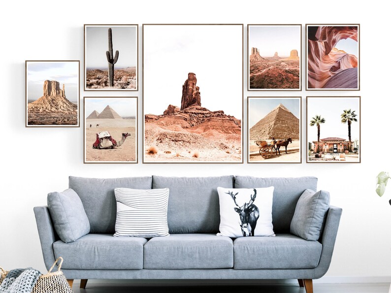 Puede incluir: Una colecci&oacute;n de impresiones enmarcadas de paisajes con escenas des&eacute;rticas, incluyendo un cactus, pir&aacute;mides y formaciones rocosas. Las impresiones se exhiben sobre un sof&aacute; gris con cojines decorativos, creando una pared de galer&iacute;a cohesiva.