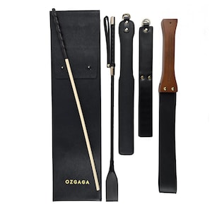 May include: A black leather flogger, paddle, and riding crop set. The set includes a black leather case with the gold text "OZGAGA". The riding crop has a braided handle and a black leather tip. The paddle has a wooden handle.