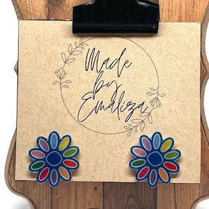 May include: A pair of colorful flower stud earrings on a wooden display stand with a sign that says "Made by Emiliza".