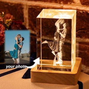 Peut inclure: Un bloc de cristal transparent éclairé, avec une image gravée d'un couple enlacé. Le bloc repose sur une base en bois. Une petite photo encadrée d'un couple est devant le bloc de cristal. Les mots "your photo" sont sur le cadre.