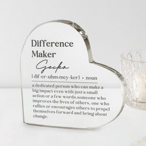 May include: A heart-shaped clear acrylic plaque featuring the printed text Difference Maker, a phonetic pronunciation guide, and a definition describing a dedicated person who makes a big impact through small actions, words, and encouragement.