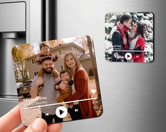 May include: Two square magnets featuring custom photo prints styled like music player interfaces. One magnet shows a family of four outdoors, while the other displays a couple in a snowy setting. Both include play buttons and song metadata text.