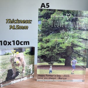 May include: Two acrylic photo blocks with images. The larger block is A5 size and features a photo of a father and son running in a park with the text "I LOVE RUNNING with Daddy!" and "Happy Father's Day - 2023. Love you always - Marcus". The smaller block is 10x10cm and features a photo of a dog in a field of yellow flowers with the text "Thank You for Loving Me".