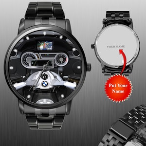 May include: Black wristwatch with a detailed motorcycle dashboard design on the face. The watch features a black metal band and a round face with gauges, a navigation screen, and a BMW logo. The back of the watch has the text "YOUR NAME".