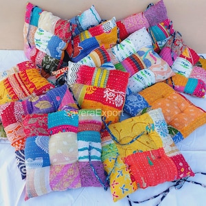 Könnte beinhalten: Eine Sammlung bunter Patchwork-Bodenkissen. Jedes Kissen besteht aus verschiedenen Stoffen in Rot-, Blau-, Gelb- und Lilatönen. Die Kissen sind zusammen angeordnet und bilden eine lebendige und strukturierte Darstellung. Der Text "SaveraExport" ist sichtbar.