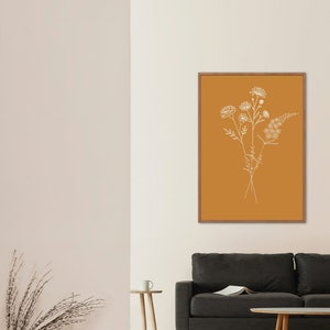 Puede incluir: Una impresi&oacute;n enmarcada con un dibujo minimalista de un ramo de flores silvestres sobre un fondo amarillo mostaza.