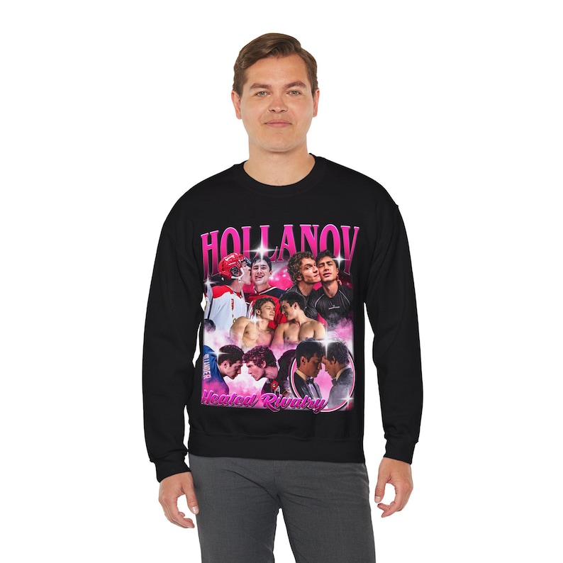 May include: Black crewneck sweatshirt featuring a graphic design with the text "HOLLANOV" in pink letters. The design includes images of several young men. Below the text is the phrase "Heated Rivalry" in pink.