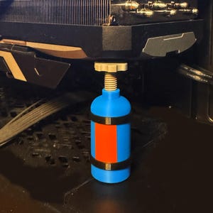 May include: A blue and orange support stand with a threaded adjustment screw, positioned under a black computer component. The stand has black bands and is designed to provide support. The MSI logo is visible.