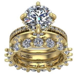 Peut inclure: Un ensemble de trois bagues en or avec des pierres précieuses claires et étincelantes. La bague de fiançailles présente une grosse pierre centrale de taille ronde. Le texte "Lavina Gold" est gravé sur la bague.