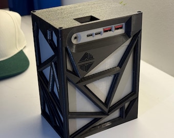 Pode incluir: Uma caixa preta impressa em 3D com um design geométrico. A caixa tem uma pequena abertura no topo e uma fila de portas no lado.