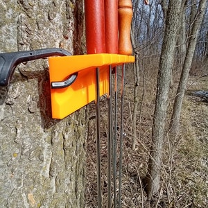 May include: Orange plastic wall mount with six metal skewers and two wooden skewers. The wall mount is attached to a tree trunk.