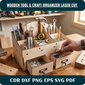Peut inclure: Un organisateur d'outils et d'artisanat en bois clair doté de plusieurs compartiments ouverts et de deux tiroirs coulissants avec des poignées en métal. L'organisateur contient divers outils à main, dont un marteau, un mètre ruban et des clés.