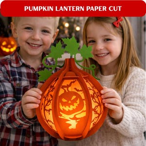 May include: An orange paper cut pumpkin lantern with a carved jack-o'-lantern face, trees, and bats. The lantern is held by two children. The text at the top reads "PUMPKIN LANTERN PAPER CUT".