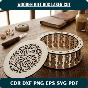 May include: A round wooden gift box with a laser-cut floral pattern on the lid and a matching openwork design on the sides. The text WOODEN GIFT BOX LASER CUT and CDR DXF PNG EPS SVG PDF is visible. The box is light-coloured wood with a smooth finish.