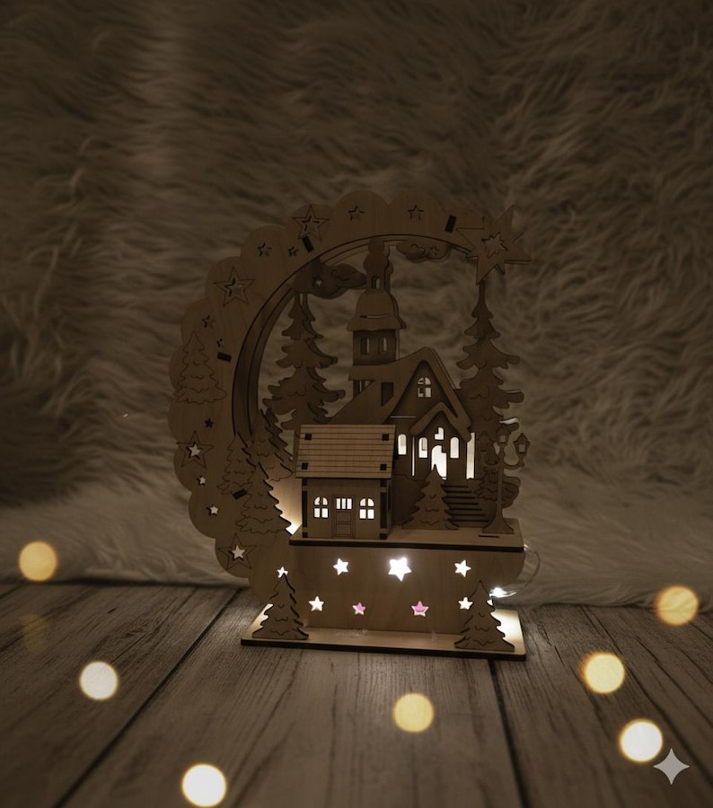 Puede incluir: Una escena de pueblo navide&ntilde;o de madera con una iglesia, &aacute;rboles y un arco decorativo. La escena est&aacute; iluminada con luces blancas c&aacute;lidas, creando un ambiente acogedor. La base presenta recortes en forma de estrella.