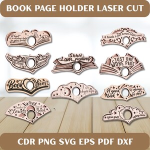 May include: Laser-cut wooden book page holders with various quotes and designs. The holders feature phrases like "A book a day keeps reality away" and "Just one more page." The holders are designed to hold a book's pages open.