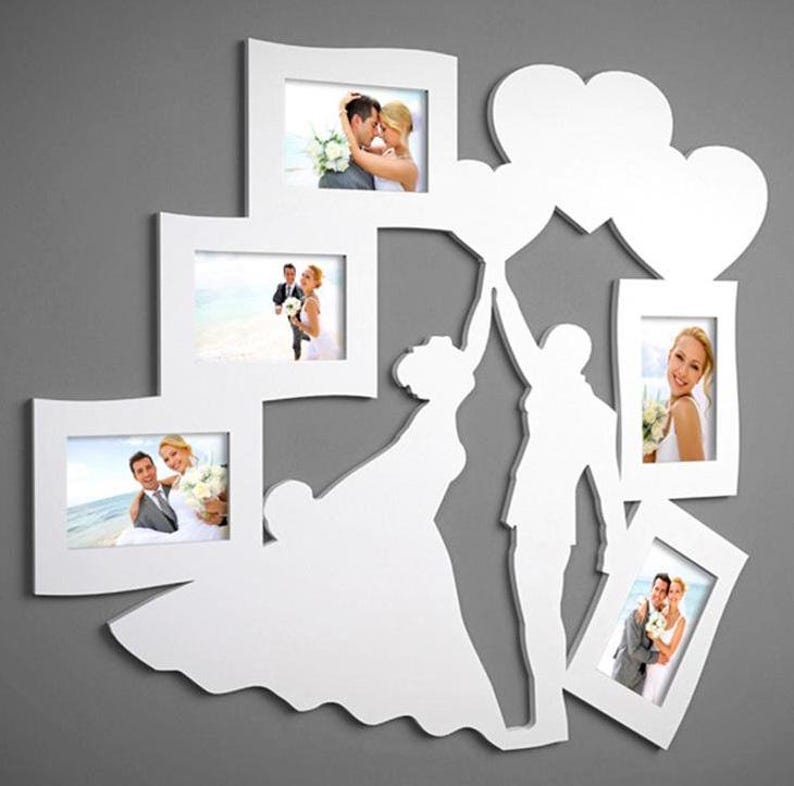 May include: White multi-photo frame with a wedding theme. The frame features several photo openings in various sizes and shapes, with a silhouette of a bride and groom holding hearts. The frame is designed to hold wedding photos.
