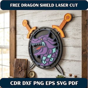 May include: A laser-cut dragon shield wall art piece. The shield features a purple dragon design with a black border, and is flanked by two orange and gray swords. The text "FREE DRAGON SHIELD LASER CUT" is at the top.