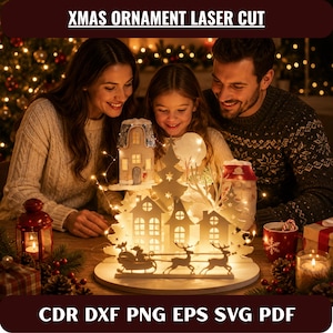 Op de afbeelding: Een wit lasergesneden houten kerstornament met een dorpsscène met huisjes, een arrenslee en rendieren, verlicht door warme kerstverlichting. De tekst XMAS ORNAMENT LASER CUT en CDR DXF PNG EPS SVG PDF is weergegeven.