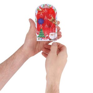 May include: A festive Christmas pinball game with a red backdrop, depicting Santa Claus, a Christmas tree, and a reindeer. The game includes point values and the words "Merry Christmas". The game is held in two hands.