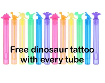 Könnte beinhalten: Ein Set mit zehn bunten Seifenblasenstäben mit Dinosaurier-Köpfen. Die Stäbe sind in einer Reihe angeordnet, unter ihnen steht der Text "Free dinosaur tattoo with every tube".