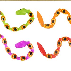 May include: Four colourful, segmented snake toys. Each snake is made of multiple connected pieces and has a different colour: green, orange, purple, and red. The snakes have black eyes and are designed to be flexible and bendable.