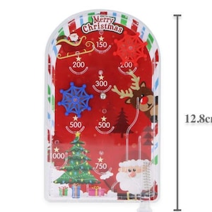 May include: A festive Christmas pinball game with a red backdrop and seasonal illustrations. The game features a Christmas tree, Santa Claus, reindeer, and snowflakes. The game is 12.8 cm tall.