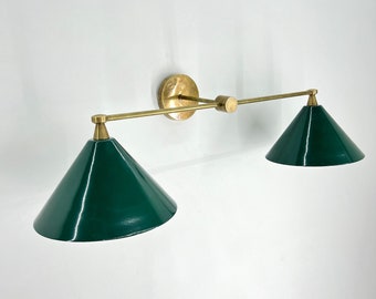 May include: A brass wall sconce with two green cone-shaped shades. The sconce has a simple, modern design.