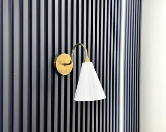 May include: A gold wall sconce with a white conical shade mounted on a black slatted wall.