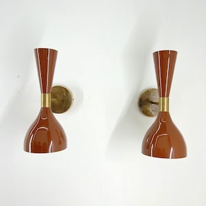 Può includere: Un paio di applique da parete marroni con dettagli in ottone. Le applique hanno un design unico e svasato e sono perfette per aggiungere un tocco di stile moderno di metà secolo a qualsiasi stanza.