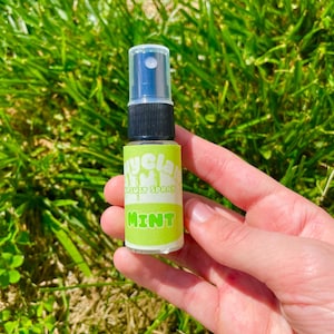 May include: A small clear plastic bottle with a black spray nozzle and a green and white label that says "Mycla  Mouth Spray  Mint".