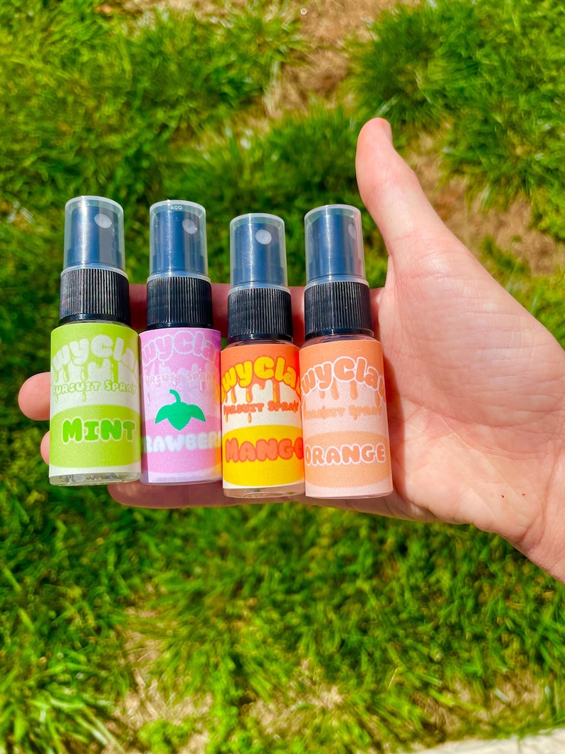 May include: Four small clear spray bottles with colorful labels. The labels have the words "Mycla" and different fruit flavors: Mint, Lavender, Mango, and Orange.
