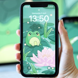 May include: A green frog with big eyes sits on a lily pad in a pond. The background is a green and white pattern of lily pads and water. The phone screen shows the time as 13:50 and the date as Wednesday 5 April.