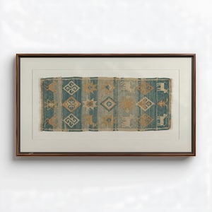 Könnte beinhalten: Gerahmte Textilkunst mit einem geometrischen Muster in Teal und Beige. Das Design umfasst Diamanten-, Stern- und Tiermotive. Das Kunstwerk ist in einem dunkelbraunen Holzrahmen gerahmt und auf einem weißen Passepartout montiert.