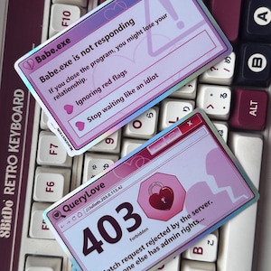 Può includere: Due adesivi rettangolari con un design di interfaccia computer rosa e viola. Uno recita "Babe.exe is not responding" e l'altro mostra "403 Forbidden". Gli adesivi sono su una tastiera bianca e bordeaux.