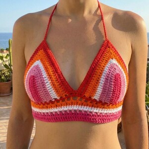 Frontal view of a handmade crochet bralette featuring lesbian pride flag colors (orange, white, and pink), perfect for summer festivals and pride events.