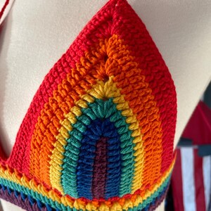 A close-up shot of a handmade crochet bikini top featuring the colors of the Pride flag.