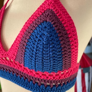 A close-up shot of a handmade crochet bikini top featuring the colors of the bisexual Pride flag.