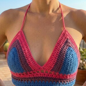 Close-up front view of a vibrant blue and pink striped crochet bikini top, showcasing the detailed knit stitches and supportive halter neck style.