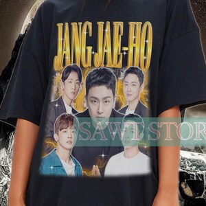 Könnte beinhalten: Schwarzes T-Shirt mit dem goldenen Schriftzug "JANG JAE-HO" und einer Collage von Bildern. Das Design hat eine Vintage-Ästhetik. Der Hintergrund zeigt eine Bergkette und ein Wirbelmuster. Es ist ein Freizeitkleidungsstück.