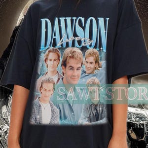 May include: Black t-shirt featuring the text "DAWSON'S CREEK" in a blue font, with a photo of the cast. The shirt is worn by a person. The background has a black and white wavy design.