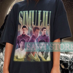 以下が含まれることがあります： 「SIMULIU」というバンドのグラフィックプリントが施された、黒色のオーバーサイズTシャツ。バンドメンバーはカラフルな衣装を着て、星空の背景の前に立っています。